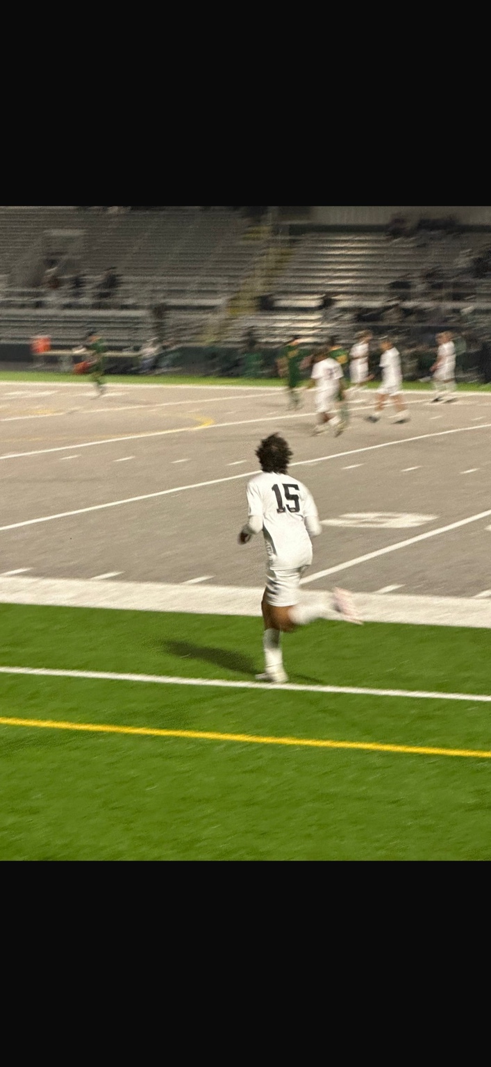 Founder Yaseen ElHaty photographed from behind in a white number 15 kit, running on a floodlit pitch